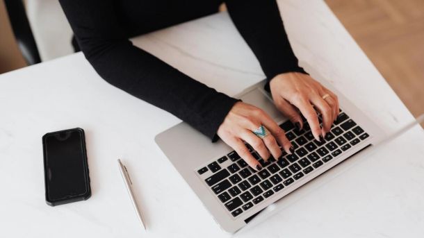 Dłonie kobiety piszącej na klawiaturze laptopa.
